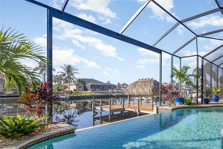 View of swimming pool featuring panoramic screen enclosure, and dock with tiki hut