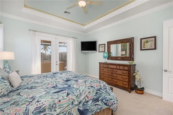 Master Bedroom featuring ceiling fan, french doors giving access to lanai, light colored carpet, tray ceilings and new Tommy Bahama bedroom set