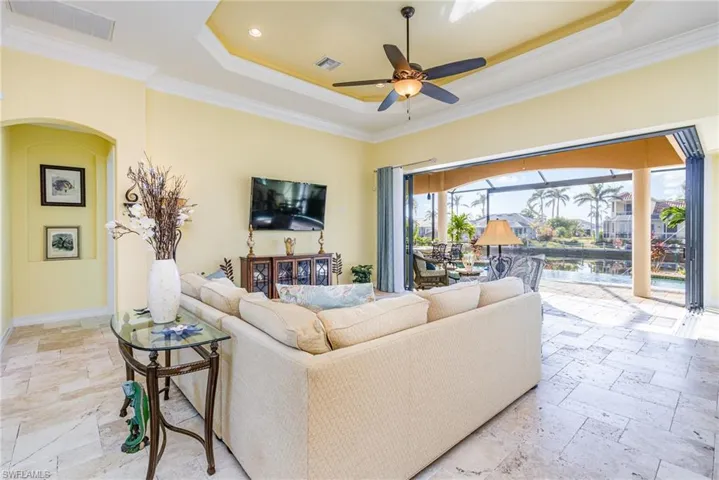 Living room featuring a tray ceiling, ceiling fan, ornamental molding