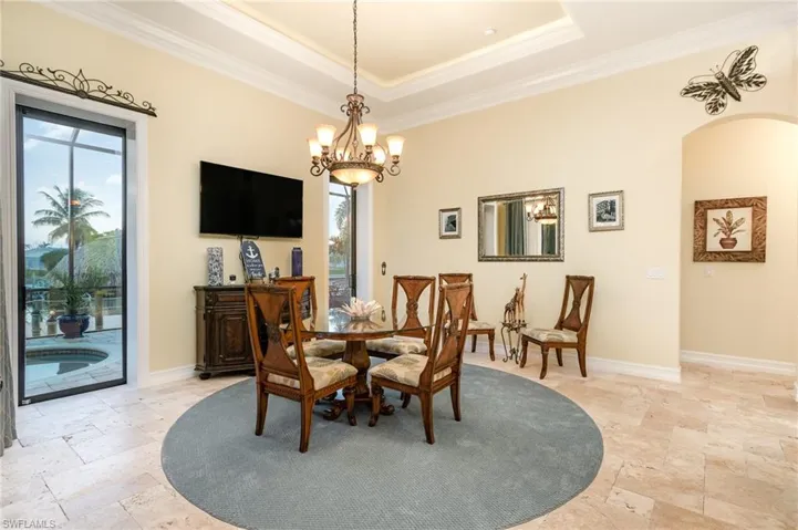 Dining room featuring a notable chandelier,  tray ceiling, and crown molding, with dual sliding doors to the outside