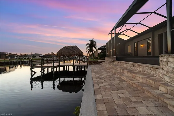 Dock area off paver sundeck area with screen enclosure and a water view