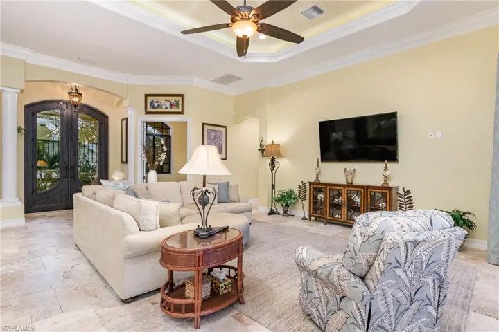 Living space with a tray ceiling, ceiling fan, and crown molding