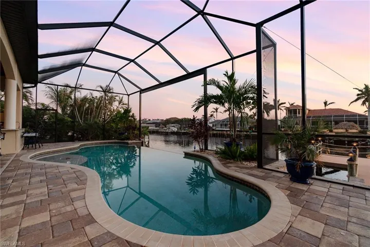 Pool at dusk featuring screen enclosure