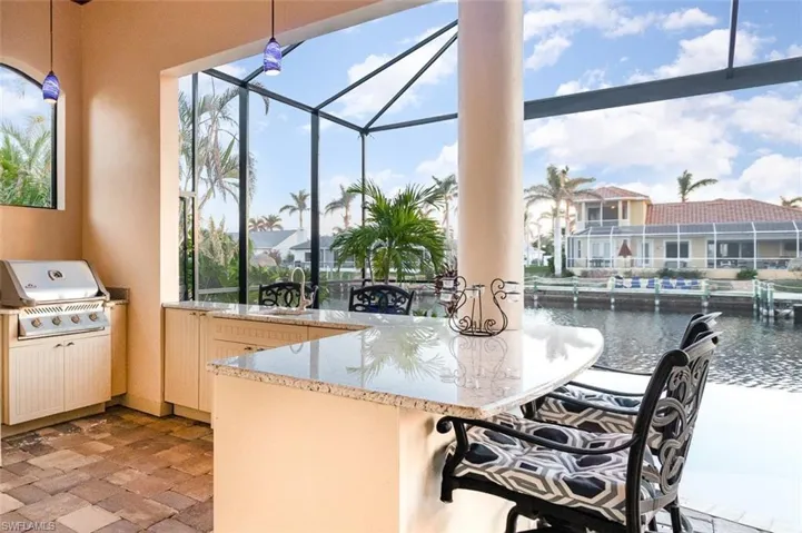 Outdoor kitchen with bar, pendant lighting, and a fabulous water view