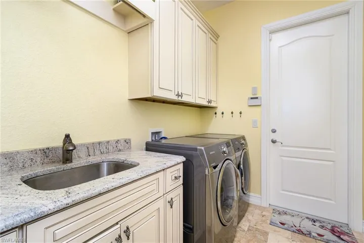 Washroom with washer and clothes dryer, sink, and cabinets