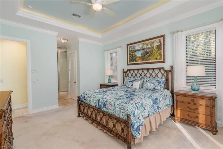 Master Bedroom featuring ceiling fan, french doors giving access to lanai, light colored carpet, tray ceilings and new Tommy Bahama bedroom set