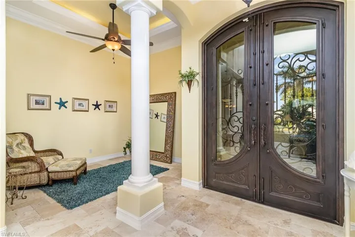Foyer view of goregeous Iron doors, entry columns and french pattern travertine flooring