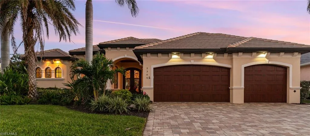 Mediterranean style home with 3 car garage, paver driveway and flat tile roof