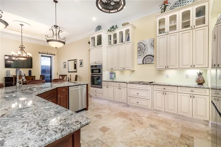 Kitchen featuring beautiful cream cabinets, sink, decorative light fixtures, and appliances with stainless steel finishes