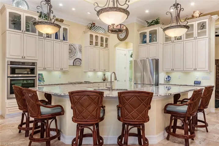 Kitchen featuring stainless steel appliances, pendant lighting, and a spacious curved island with seating for 6