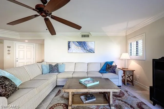 Tiled living room featuring crown molding and ceiling fan