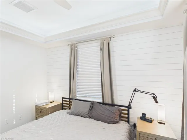 White shiplap accent wall with a tray ceiling and crown molding