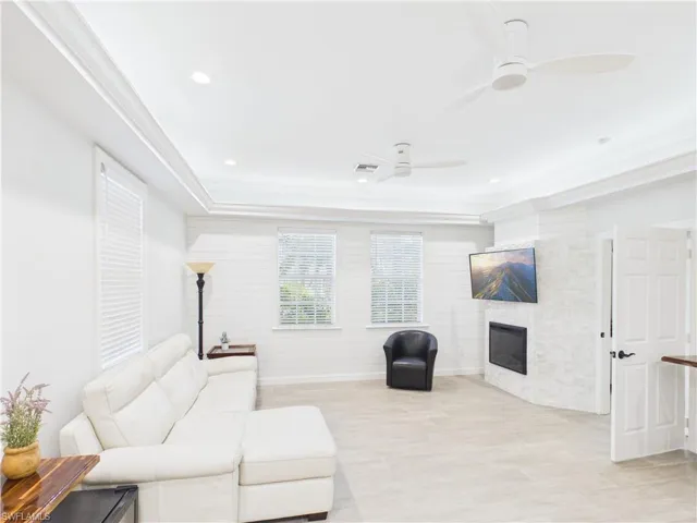 Spacious interior featuring tray ceilings with recessed lighting, two ceiling fans, and wood-finish flooring