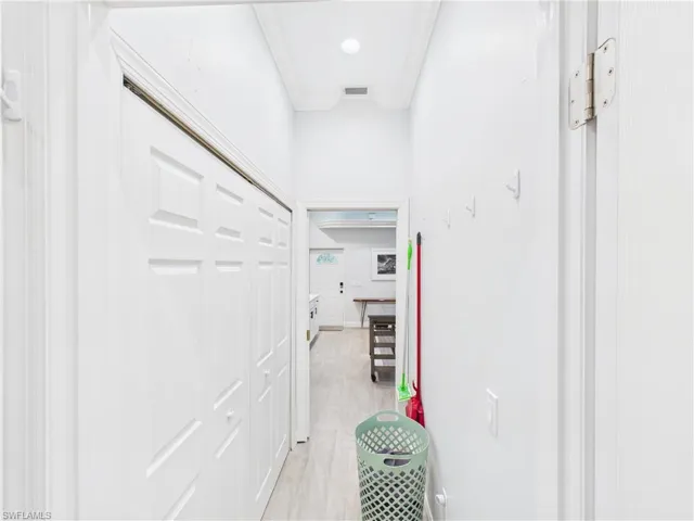 Hallway with wood-finish flooring, bi-fold closet doors, crown molding, recessed lighting, and white walls