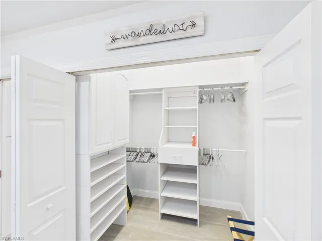 Custom closet system featuring white cabinetry, multiple shelving units, and ample hanging space