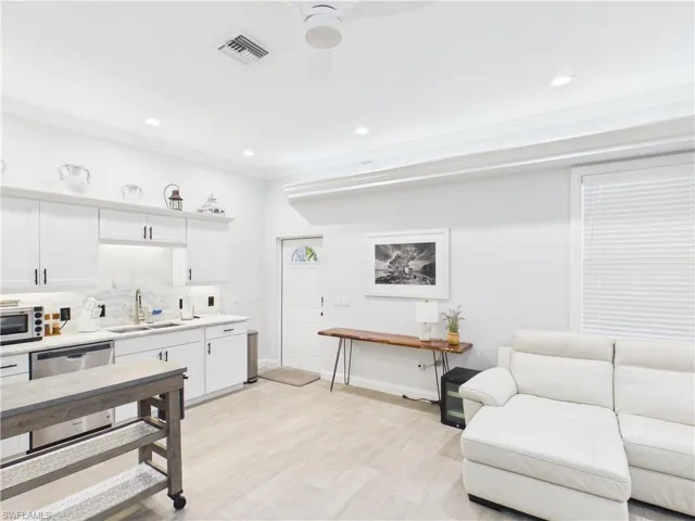 Open-concept living space featuring a full kitchen with white cabinetry, stainless steel appliances, and a marble-patterned backsplash