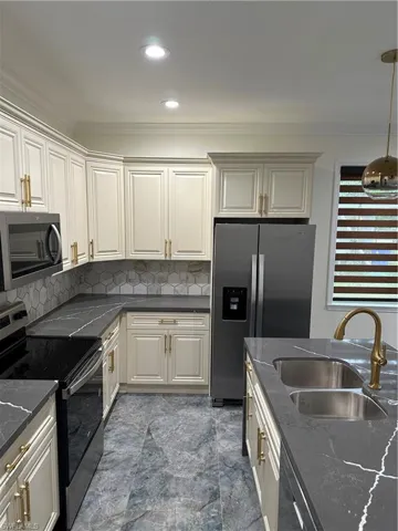 Kitchen featuring stove, refrigerator, ornamental molding, backsplash, and marble finish floors