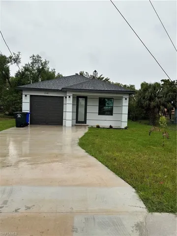 View of front facade with concrete driveway, an attached garage, a front yard, and roof with shingles