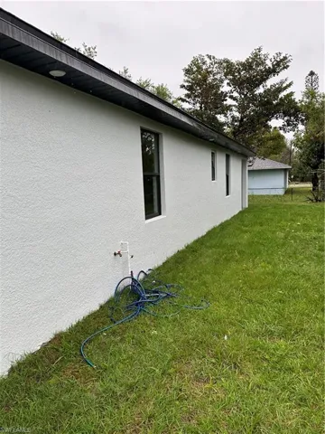View of side of home with stucco siding and a lawn