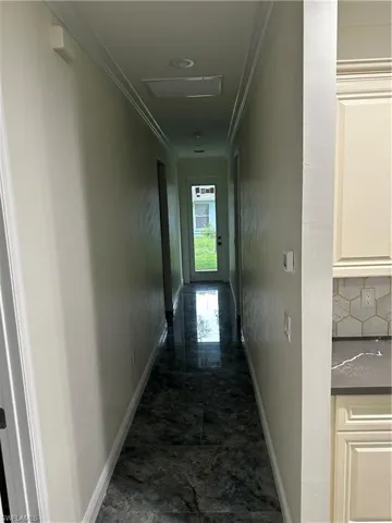 Corridor featuring ornamental molding and dark marble finish floors