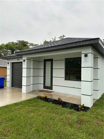 View of front facade with an attached garage, a shingled roof, a front lawn, and driveway