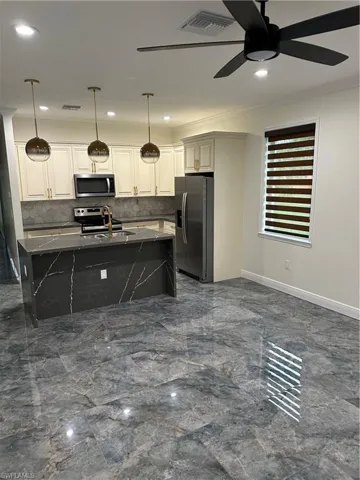 Kitchen featuring refrigerator, a ceiling fan, decorative backsplash, range, and dark marble finish flooring