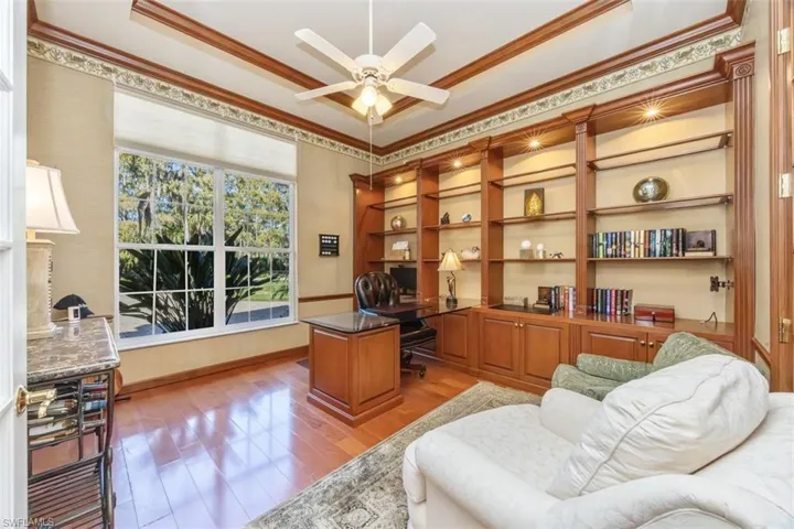 Office featuring a tray ceiling, light wood-style flooring, crown molding, and ceiling fan