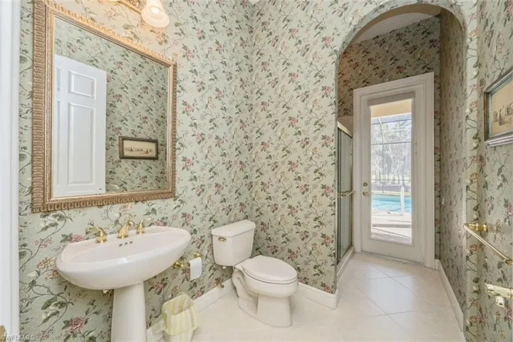 Bathroom with wallpapered walls, tile patterned floors, and a stall shower