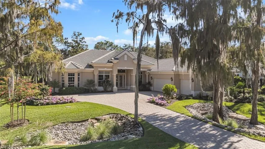 View of front of home with decorative driveway, a tile roof, stucco siding, a front lawn, and french doors