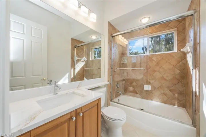 Full bathroom featuring enclosed tub / shower combo, vanity, and light tile patterned floors
