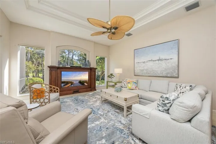 Living area featuring a tray ceiling, crown molding, and a ceiling fan