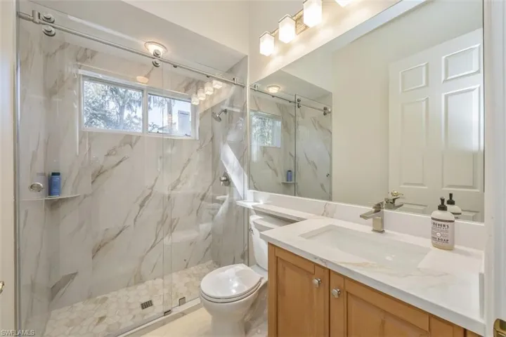 Bathroom featuring vanity and a marble finish shower