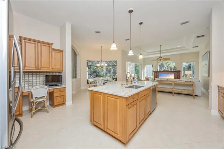 Kitchen with a tray ceiling, stainless steel appliances, a chandelier, built in desk, and light tile patterned floors