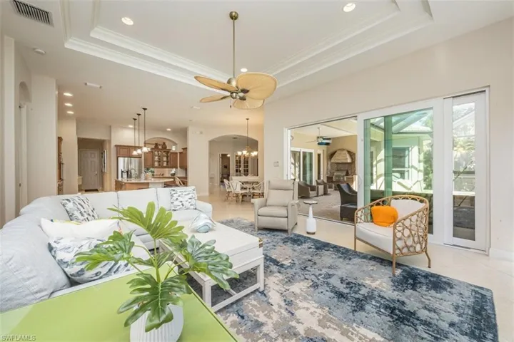 Living room featuring a chandelier, arched walkways, recessed lighting, a tray ceiling, and light tile patterned floors