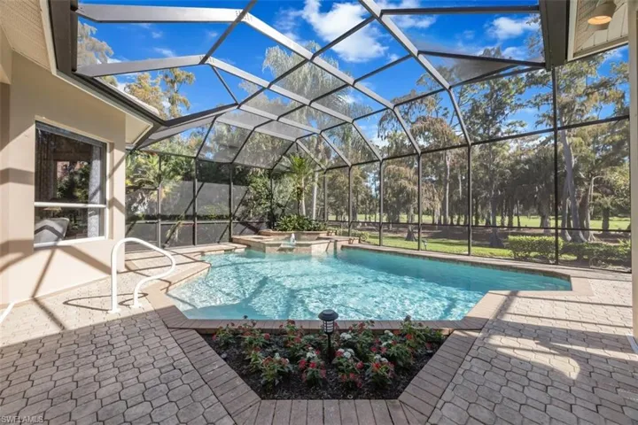 View of swimming pool featuring a lanai, a sunroom, a pool with connected hot tub, and a patio