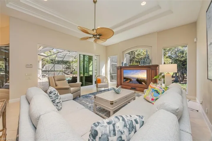 Living room with light tile patterned flooring, a sunroom, a raised ceiling, healthy amount of natural light, and recessed lighting