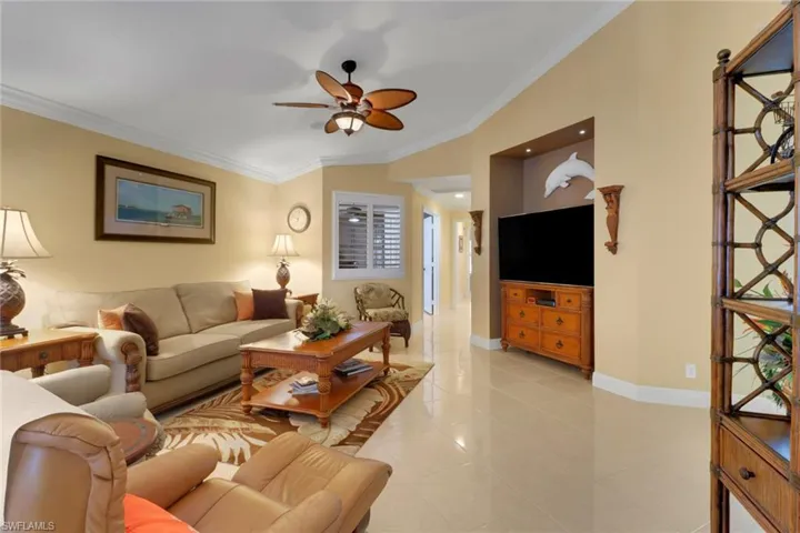 Tiled living room featuring ceiling fan and crown molding