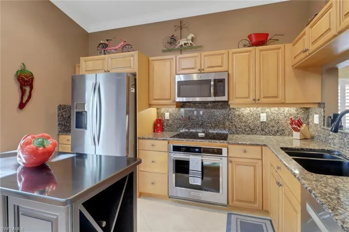 Kitchen with stainless steel appliances, sink, tasteful backsplash, light brown cabinets, and crown molding