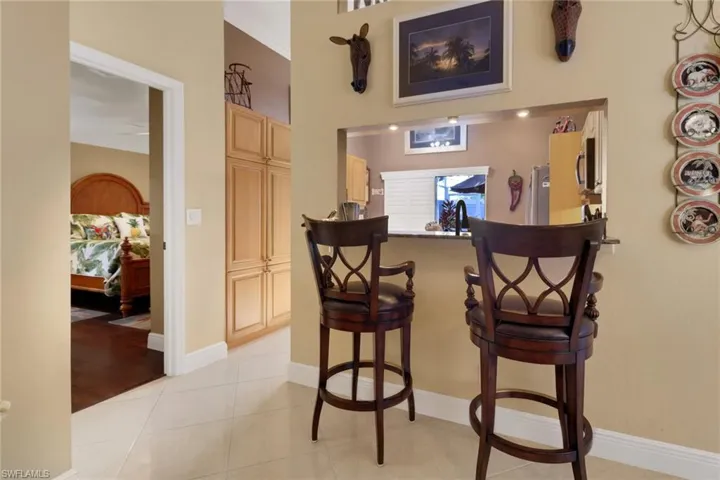 Bar featuring light brown cabinetry, stainless steel fridge, light hardwood / wood-style floors, and crown molding