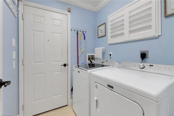 Washroom featuring cabinets, separate washer and dryer, light tile patterned floors, and crown molding