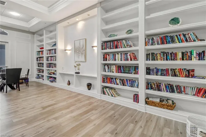 Home office with light wood-type flooring, built in features, and crown molding