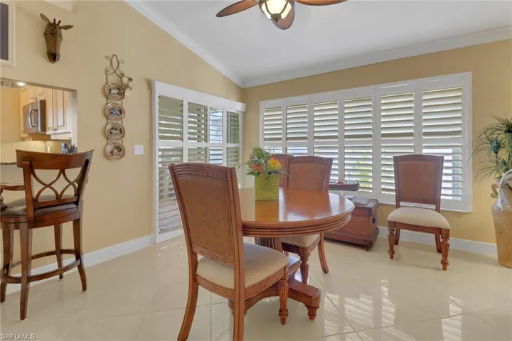 Tiled dining area featuring ceiling fan, crown molding, and vaulted ceiling