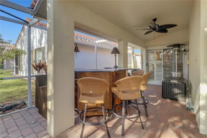 View of patio with glass enclosure, ceiling fan, and exterior bar