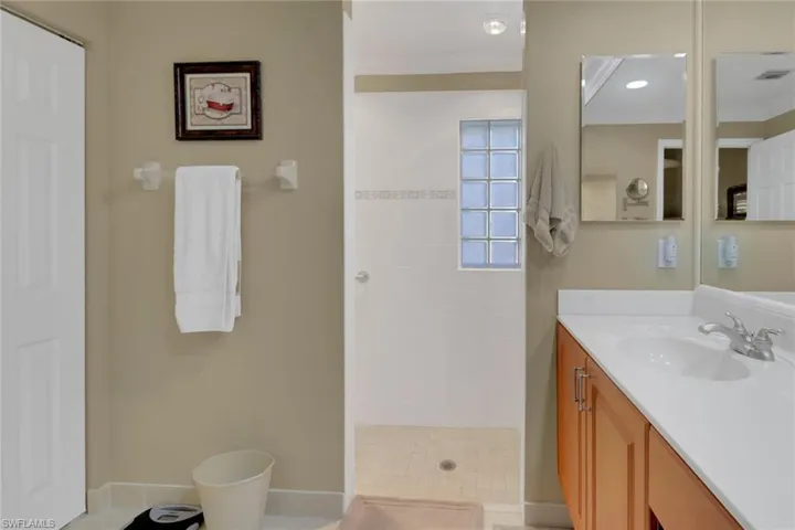 Bathroom with walk in shower, vanity, tile patterned floors, and crown molding