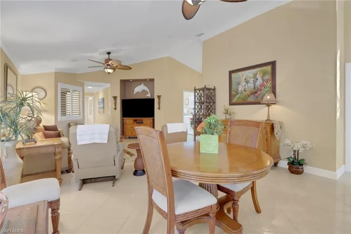 Dining room with lofted ceiling, light tile patterned floors, a healthy amount of sunlight, and crown molding