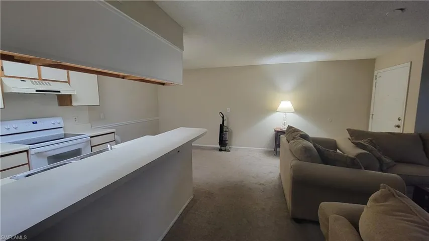 Kitchen featuring white cabinets, a textured ceiling, light carpet, and white electric range oven