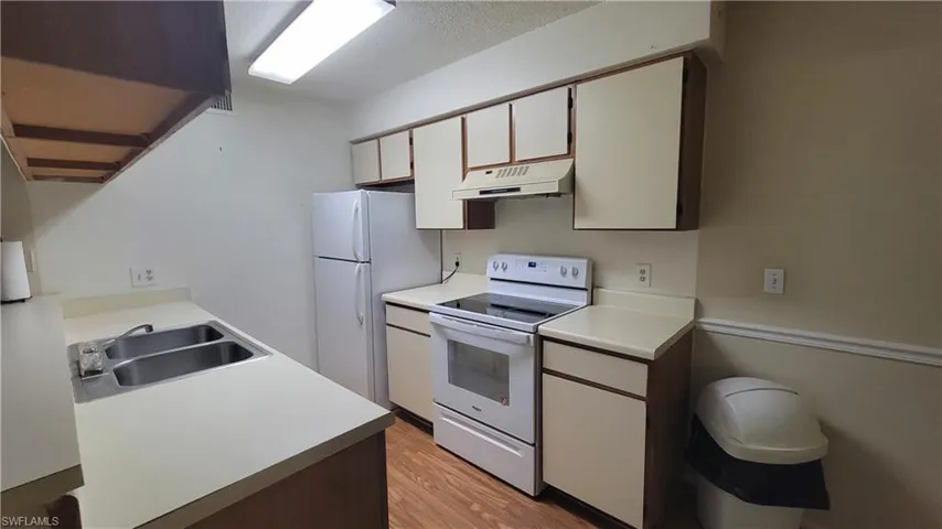 Kitchen featuring light wood-type flooring, white appliances, white cabinetry, and sink