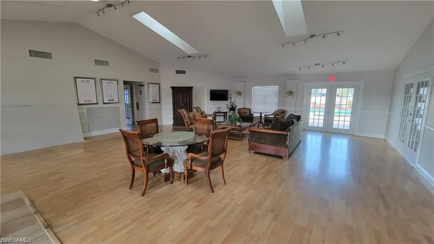 COMMUNITY  Dining area featuring light hardwood / wood-style flooring, a skylight, french doors, and track lighting