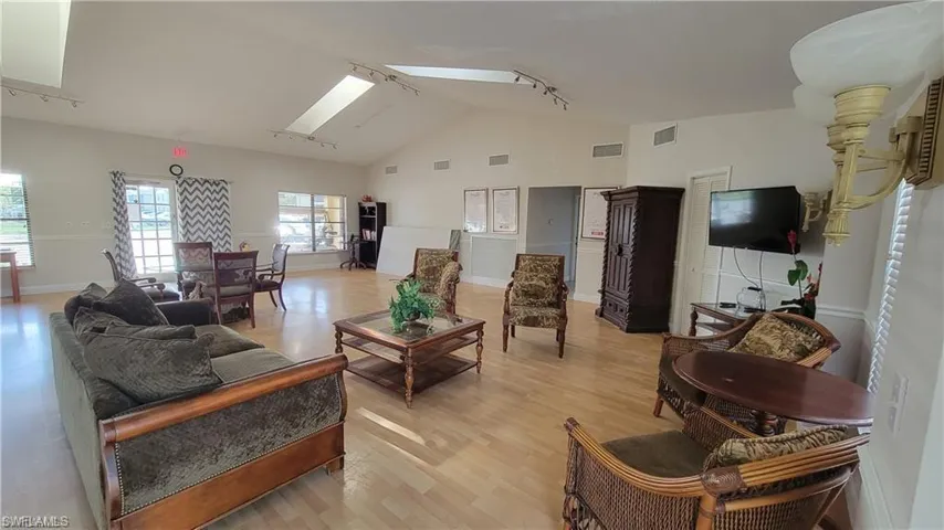 COMMUNITY Living room with track lighting, vaulted ceiling with skylight, and light hardwood / wood-style floors