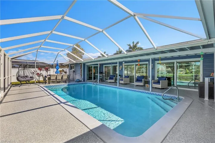 Screened-in outdoor living space featuring a rectangular swimming pool, expansive pool deck, and a screened enclosure